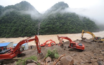 Rescuers use heavy machinery to search for signs of life in the Fujian landslide site.
