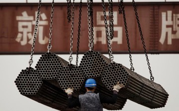 A Chinese steel worker helps load steel rods onto a large truck for transport at a plant on April 6, 2016 in Tangshan, Hebei province, China. 