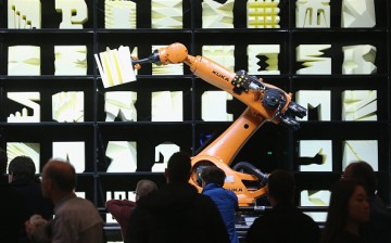Visitors watch a Kuka robot perform precise movements at a technology trade fair on March 16, 2015 in Hanover, Germany.