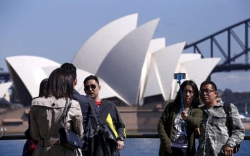 Chinese tourists take pictures of themselves with the Sydney Opera House in the background.