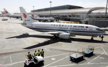 Workers stand while waiting to unload cargo from an airplane in Beijing airport.
