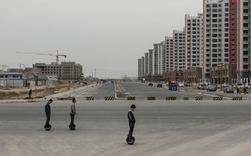 Photo taken on May 7, 2016 shows locals riding a one-wheel electric scooter by a newly built residential compound in Lanzhou New Area in Gansu Province.