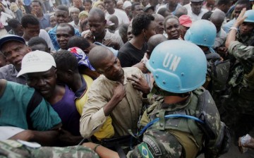A United Nations peacekeeper holds back voters as they try to form a line in front of a polling center on Feb. 7, 2006 in Port-au-Prince, Haiti.