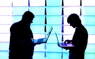 Participant hold their laptops in front of an illuminated wall at the annual Chaos Computer Club (CCC) computer hackers' congress, called 29C3, on December 28, 2012 in Hamburg, Germany. 