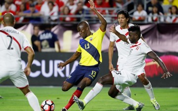 Ecuador striker Enner Valencia passes against three Peru defenders.