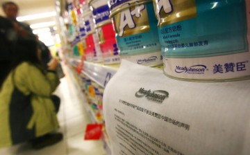 Customers buy milk powder in front of Mead Johnson milk powder products, where an announcement reading 'the callback of overseas Mead Johnson products will not involve the Chinese market' is placed, at a supermarket on February 25, 2006 in Ningbo of Zheji