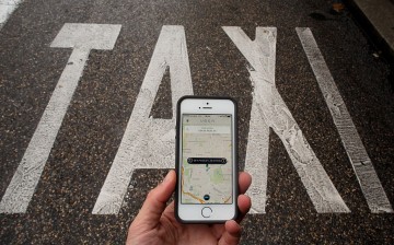 Uber app being used to select a pick up location next to a taxi lane in Madrid, Spain.