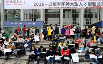 Take it sitting down: Job hunters turn to the traditional way of looking for work as they scan papers in front of a labor market on Feb. 27, 2016, in Chengdu, Sichuan Province.