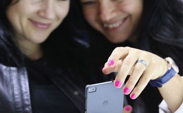 Two women look at a Huawei Honor phone