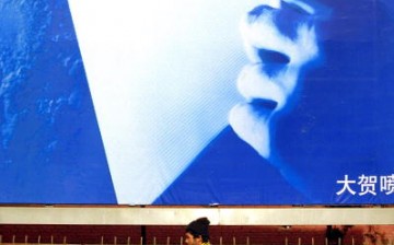 A man pedals his tricycle in front of a billboard featuring an advertisement for a Chinese official website Jan. 30, 2002 in Beijing, China. 