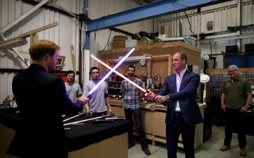 Prince Harry (L) and Prince William, Duke of Cambridge, try out light sabres during a tour of the Star Wars sets at Pinewood studios on April 19, 2016 in Iver Heath, England. 