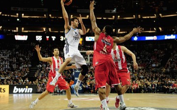 Real Madrid shooting guard Rudy Fernandez (in white) passes off against three Olympiacos Piraeus defenders.