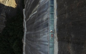 A visitor lies down on a skywalk glass bridge in central China's Hunan Province, July 8, 2016. 