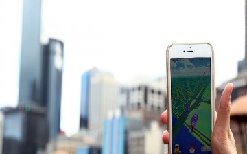 A man holds up his phone as he plays the Pokemon Go game on July 13, 2016 in Melbourne, Australia. The augmented reality app requires players to look for Pokemon in their immediate surroundings with the use of GPS and internet services turning the whole w