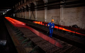 A worker walks past a hot roller steel at a steel manufacturing plant in Changzhou, Jiangsu Province.