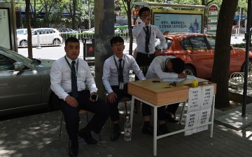Real estate agents sell new homes in the sidewalk in Beijing.