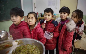 Children of migrant parents wait in line for lunch in school.