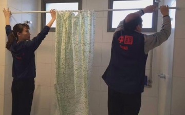 Members of the Chinese gymnastics team putting the shower curtains in their quarters at the Olympic Village in Rio. 