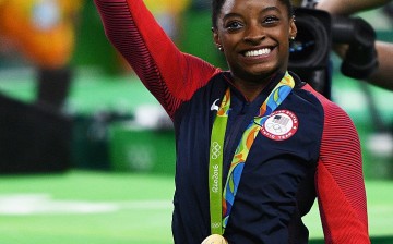 Simone Biles of the United States waves to fans with her gold medal after the medal ceremony for the Artistic Gymnastics Women's Team on Day 4 of the Rio 2016 Olympic Games.
