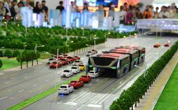 Visitors look at a scale model of a Transit Elevated Bus (TEB) during a demonstration at the19th China Beijing International High-tech Expo (CHITEC) held in May in Beijing.
