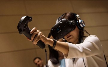 A visitor tries a special headset and trackpad made by American HTC company to experience virtual reality during the 2016 Tianjin World Economic Forum.