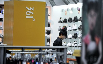 A customer looks at sneakers and sports shoes displayed in a sportswear store in Beijing.