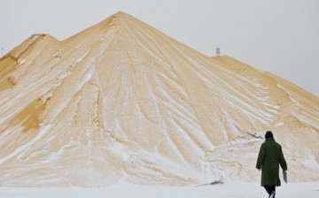 A farmer walks past a pile of corn at a state grain reserves depot on Dec. 19, 2008, in Yushu in Jilin Province, China.