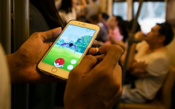 A man plays Pokemon Go while commuting home from work inside a train in Bangkok, Thailand August 24, 2016. 