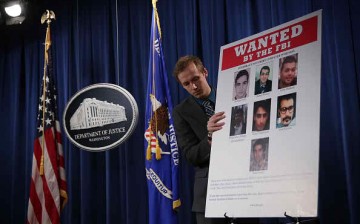 A Department of Justice employee put up a poster of indicted hackers in Washington on March 24, 2016