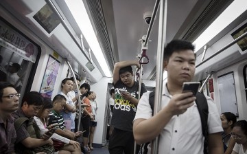 The more the merrier: With almost everyone owning a smartphone, scammers are always on the hunt for new victims. (Above) Some train passengers in Shenzhen tinker with their phone on Aug. 23, 2016.