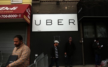 Men stand in front of a Uber sign as drivers protest the company's recent fare cuts and go on strike in front of the car service's New York offices.
