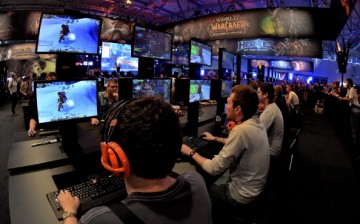 Visitors try out the massively multiplayer online role-playing game 'World Of Warcraft' at the Blizzard Entertainment stand at the 2014 Gamescom gaming trade fair.