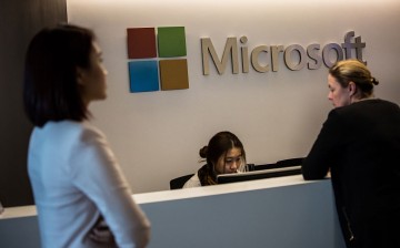 Employees walk past the reception booth of Microsoft's new office in Hong Kong.