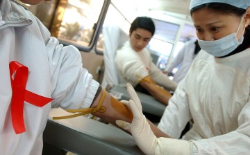 A nurse prepares to collect blood from a donor during a volunteer blood donation campaign to mark World AIDS Day.