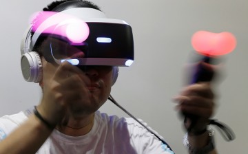  A visitor wearing a PlayStation VR headset plays a video game in the Sony Interactive Entertainment Inc. booth.