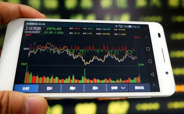 An investor uses a mobile phone to look at stock information in a stock market in Huaibei, Anhui Province.