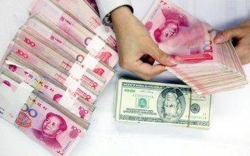A clerk counts stacks of Chinese yuan and U.S. dollars at a bank on July 22, 2005, in Shanghai, China.