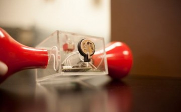 Researchers modified a hand-crank flashlight by installing a small supercapacitor (in the center) in a conventional button battery case. The light continued to glow long after the cranking stopped, th
