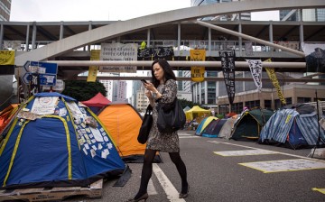 A businesswoman walks past tents used by pro-democracy protesters at the Admiralty protest site on Nov. 13, 2014 in Hong Kong, Hong Kong. 