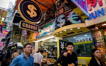 Pedestrians walk past a money exchange booth in Hong Kong.