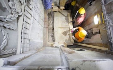 Workers remove a marble slab covering the original stone burial bed where Jesus Christ is said to have been laid to rest after being crucified. A layer of loose fill material is seen beneath.