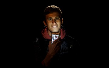 Diego Silva poses for a picture as he illuminates himself with his mobile phone at Puerta del Sol Apple Store facade the dawn before the company launches their Iphone 7 and 7 Plus on September 16, 2016 in Madrid, Spain.