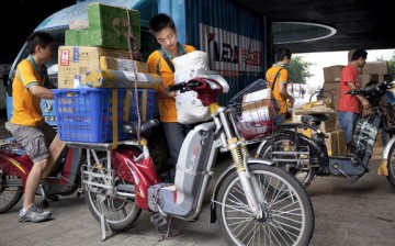 A courier loads packages for delivery using an electric bicycle in Shenzhen, Guangdong Province.