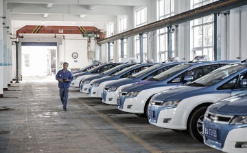 A man walks past a fleet of BYD Co. electric taxis in a charging station in Taiyuan, Shanxi Province.