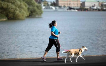 A woman runs with a dog on leash. 