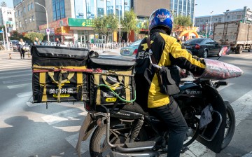 A motorcycle-riding delivery man waits for the traffic signal light to turn green in Yanji, Jilin Province.