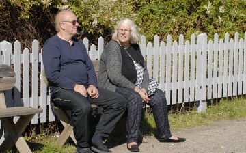 Retired senior couple seated in garden chairs appear relaxed looking out