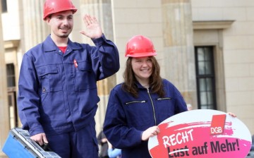 Two demonstrators posing as unequally paid constructions workers, the woman holding a sign reading 'Not a Wish But a Right to More!’ demonstrate during the 'Equal Pay Day' demonstration. 