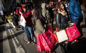 Shoppers carry recent purchases through Herald Square on the morning of November 28, 2014 in New York City. The Friday after Thanksgiving, also known as Black Friday, traditionally marks the beginning of the Holiday season. 