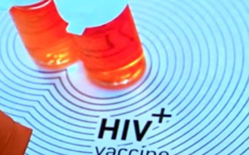 Two medicine bottles are placed just above an HIV positive vaccine sign. 